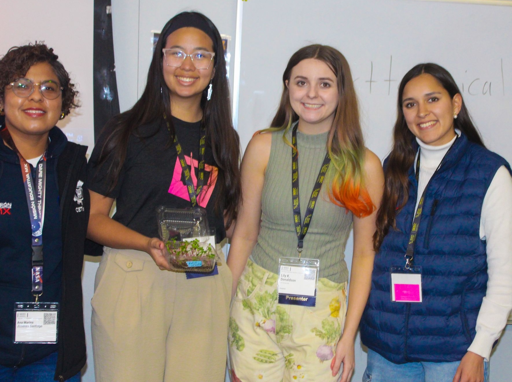 Lily and other educators at SEEC Astrobotany workshopping. One is holding a microgreen sheet.